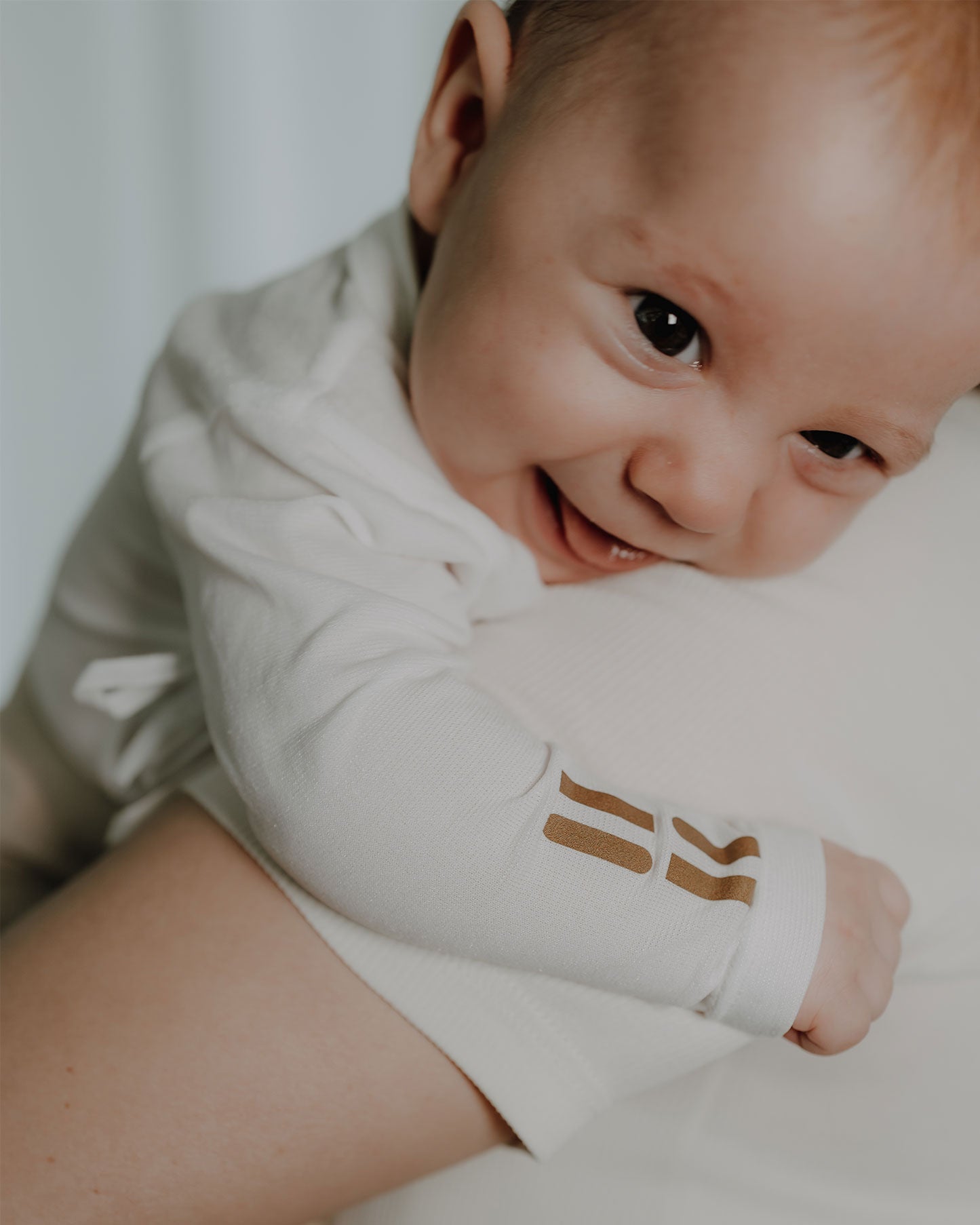 Baby wird auf dem Arm gehalten und trägt hautfreundlichen TRUSTGARN Body für empfindliche Haut