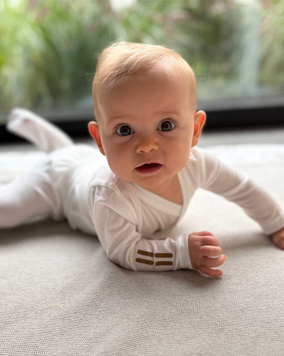 Baby trägt weißen TRUSTGARN Body aus hautfreundlichem, atmungsaktivem Stoff für empfindliche Haut und Neurodermitis