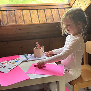 Mädchen mit empfindlicher Haut bastelt in weißer TRUSTGARN Kleidung bei Tageslicht.